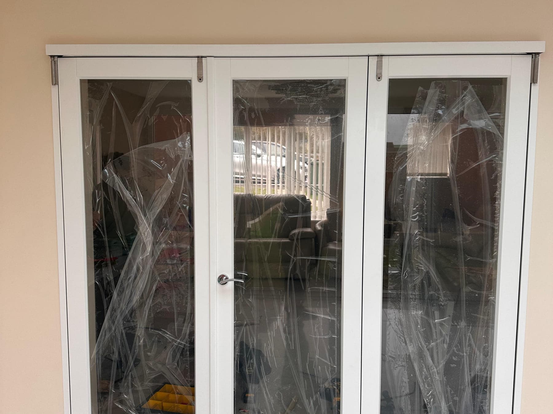 The same opening with three glazed white doors hung in it, protective film still on the glass