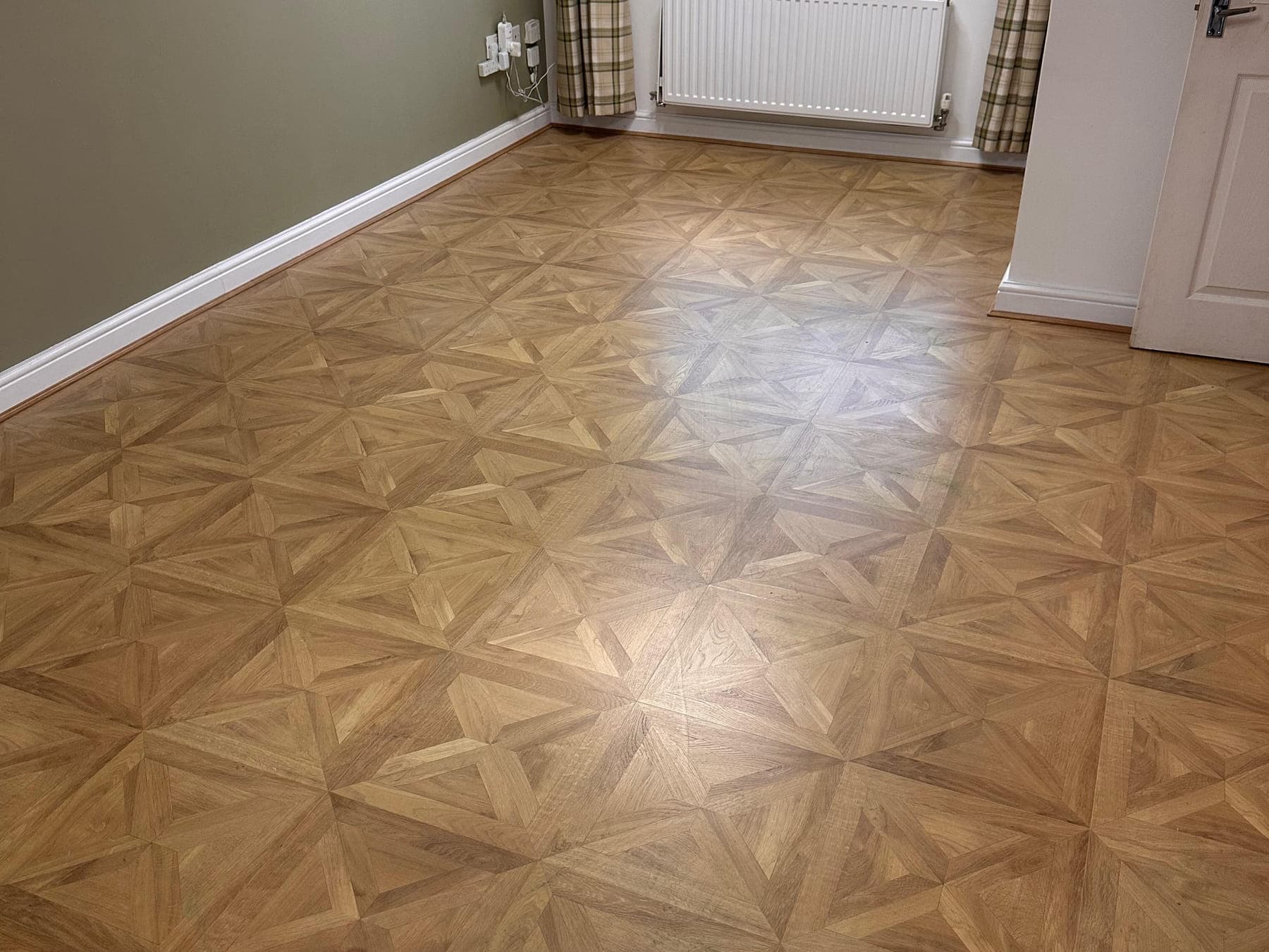 The same room with parquet-effect flooring laid, running square to the window wall