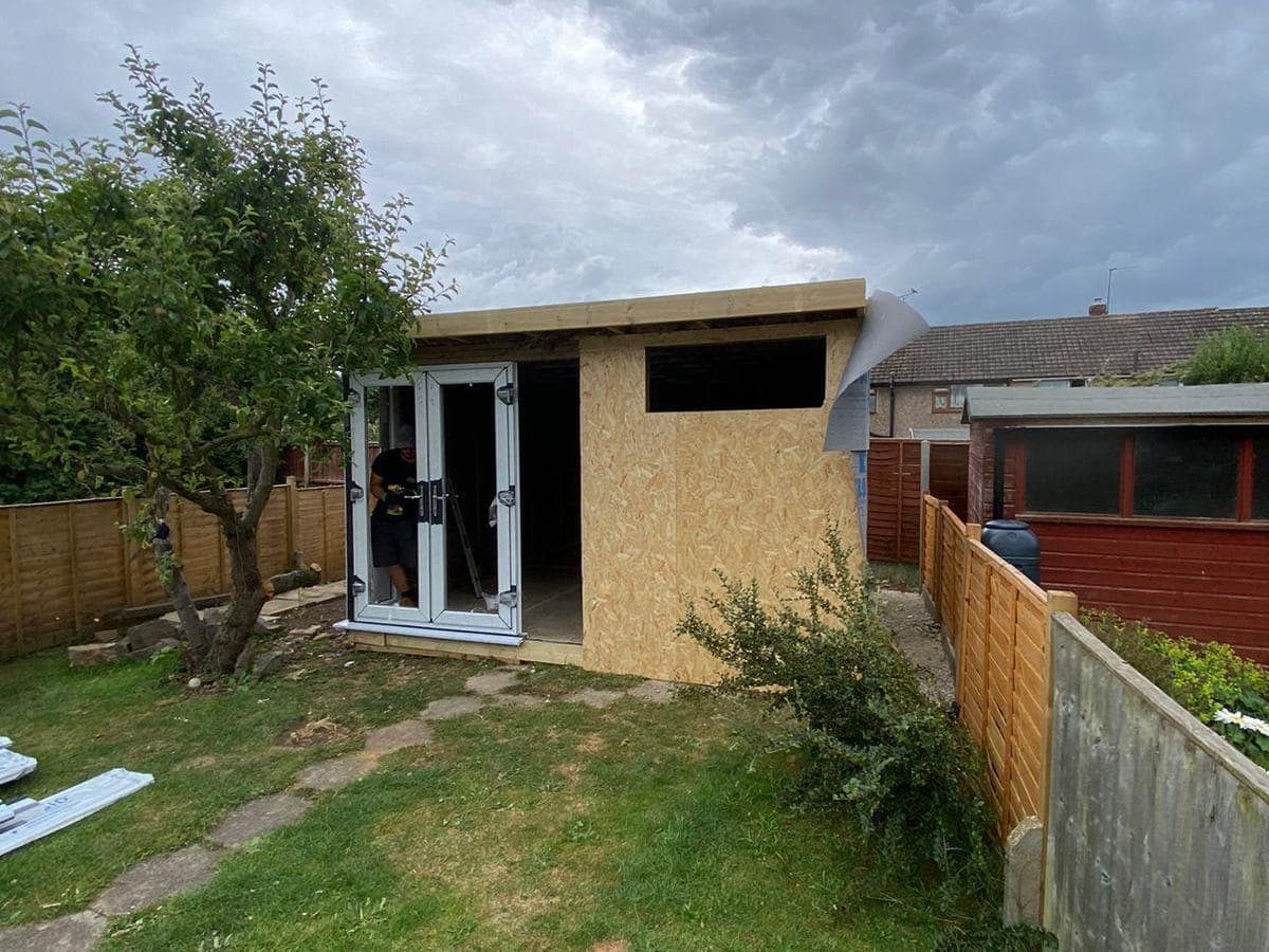 A garden room part-built, still in bare OSB sheathing with the doors fitted and no cladding