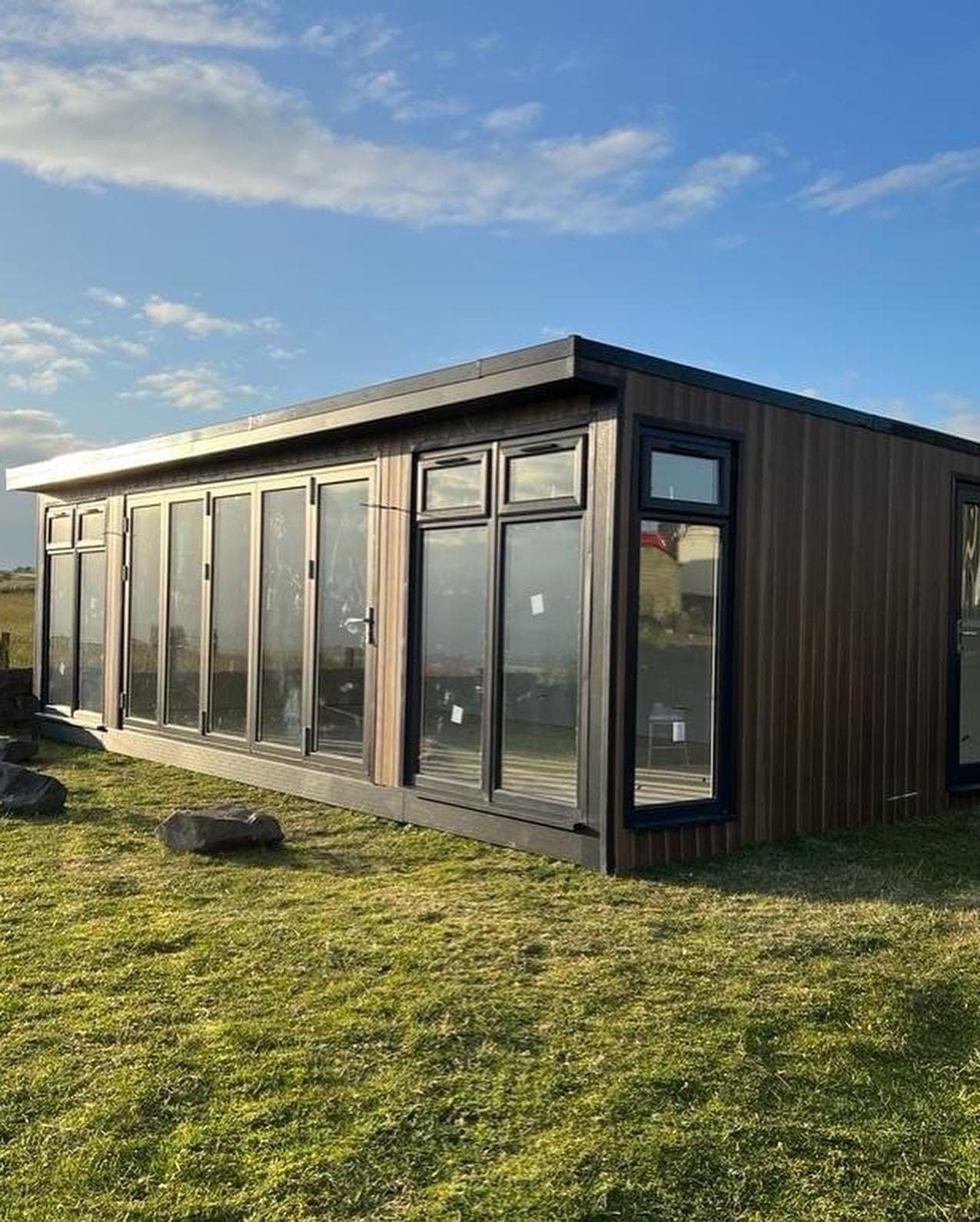 A timber-clad garden room with a flat roof and a run of anthracite bi-fold doors